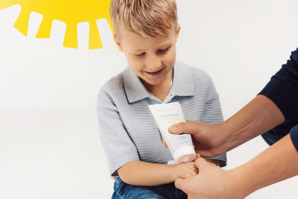 Kind wird mit Sonnencreme mit Lichtschutzfaktor 30 am Arm eingecremt
